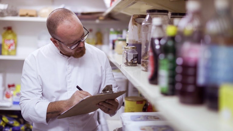chef taking inventory of stock with clipboard and pen