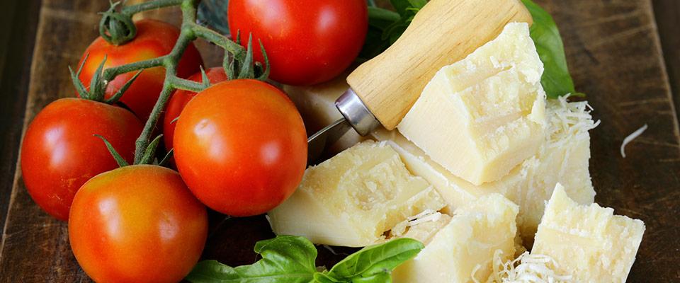 Fresh parmesan cheese with tomatoes and basil on wooden board