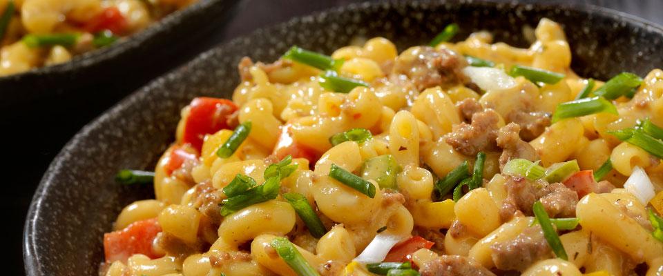 Bowl of macaroni and cheese with hamburger and garnishes