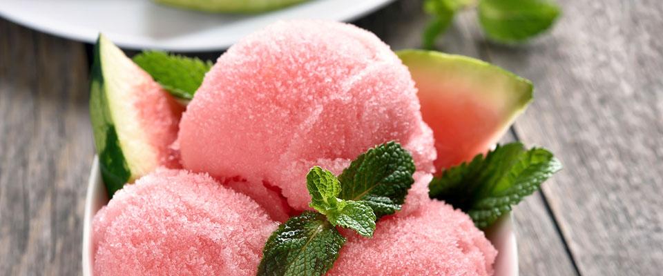 Bowl of watermelon sorbet with mint served on outdoor wooden surface
