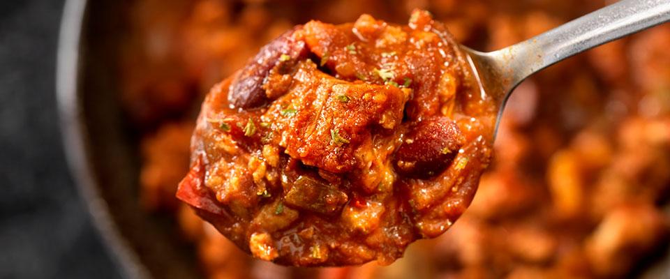 Spoon over bowl of steak chili with kidney beans
