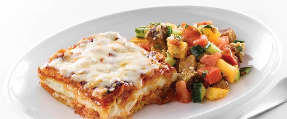 Plate of whole grain lasagna with meat sauce and grilled panzanella salad