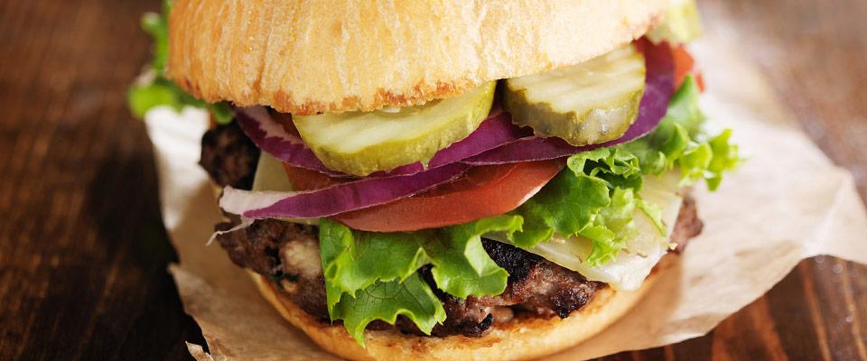 Gourmet hamburger on wax paper and wooden surface