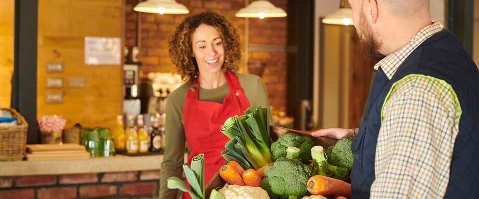 Farmer delivering a basket of local produce to a foodservice cafe owner