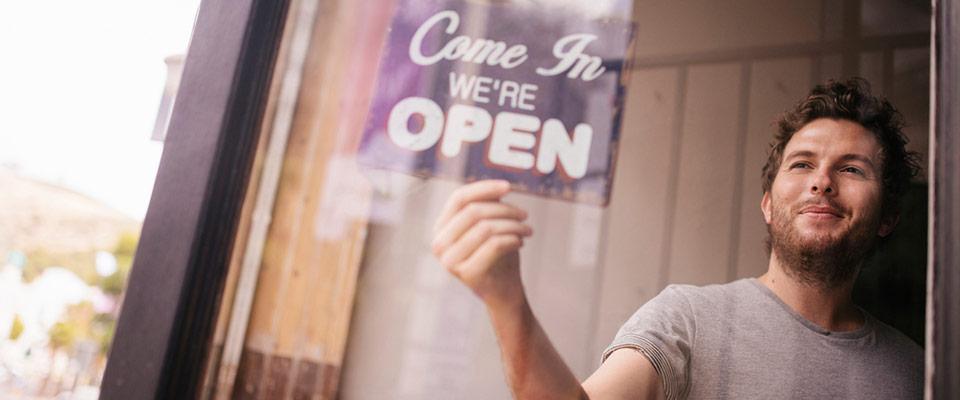 Man turning over open sign in shop window