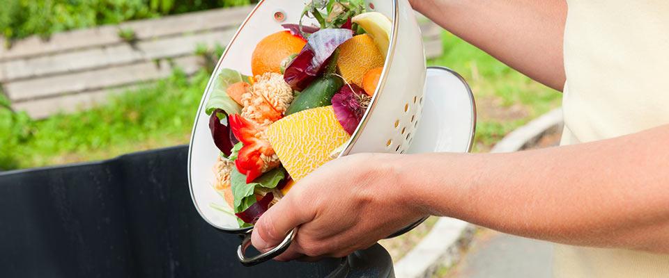 Person dumping food waste into trash can