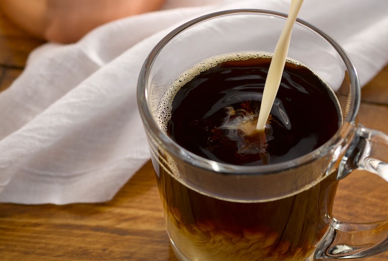 coffee creamer being poured into coffee
