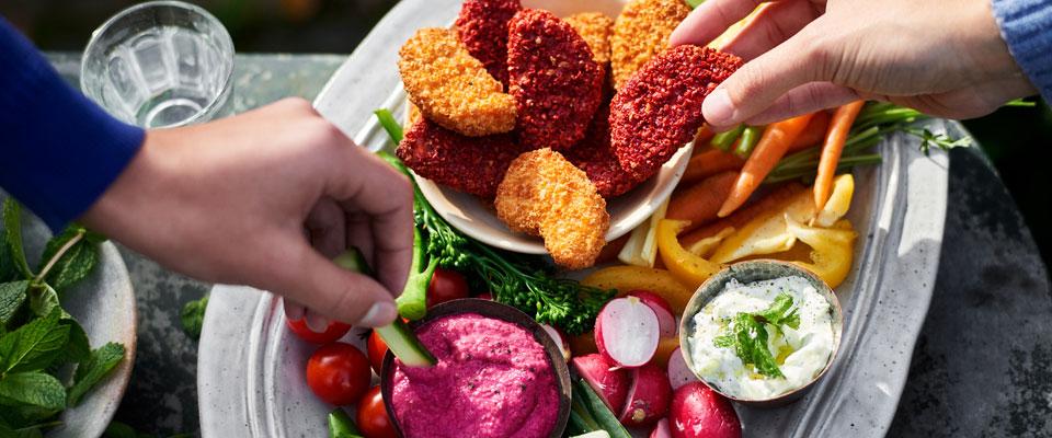 Two people sharing a healthy snack of vegetable dips