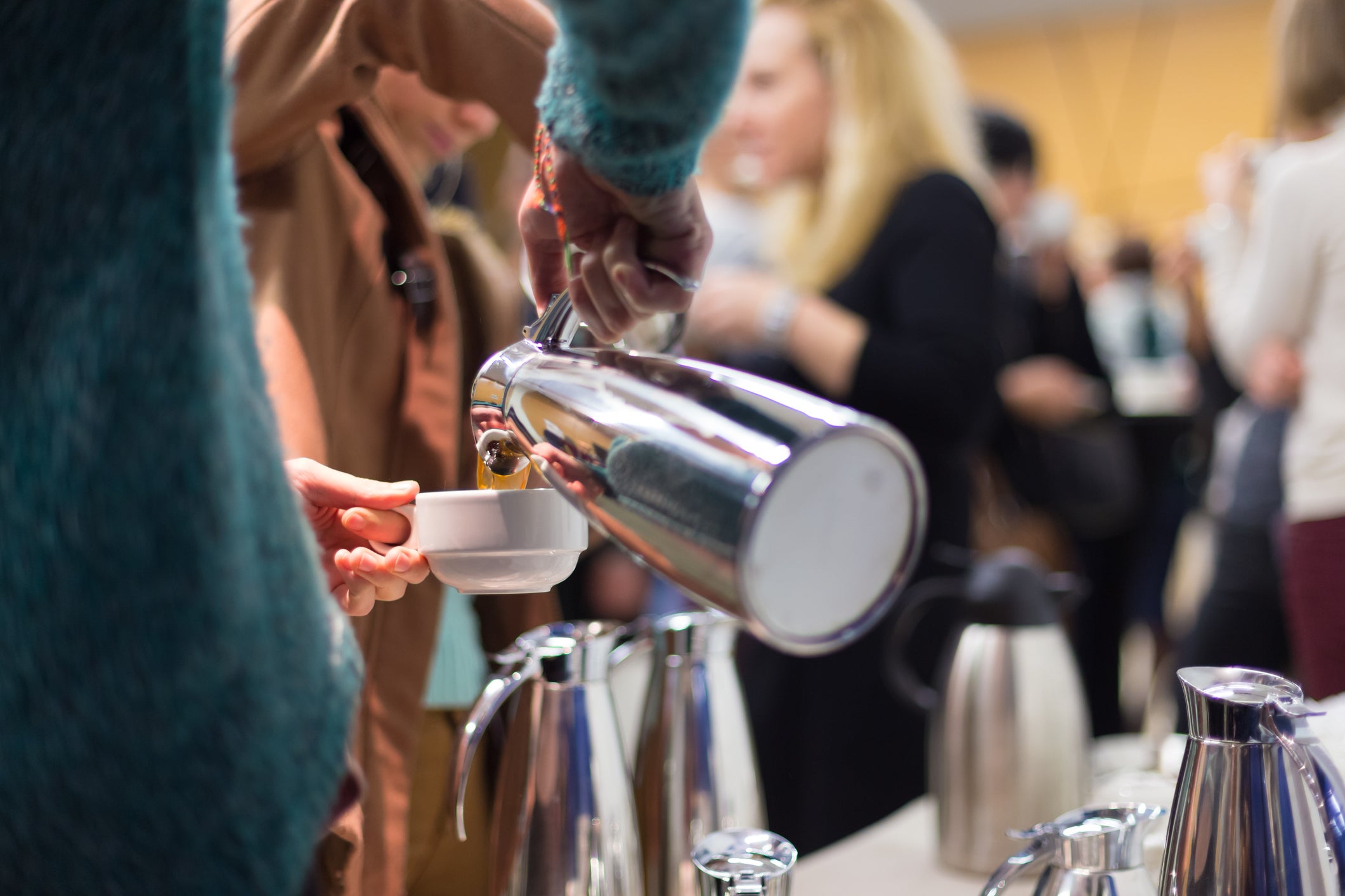 Person pouring from a carafe in a crowded dining hall