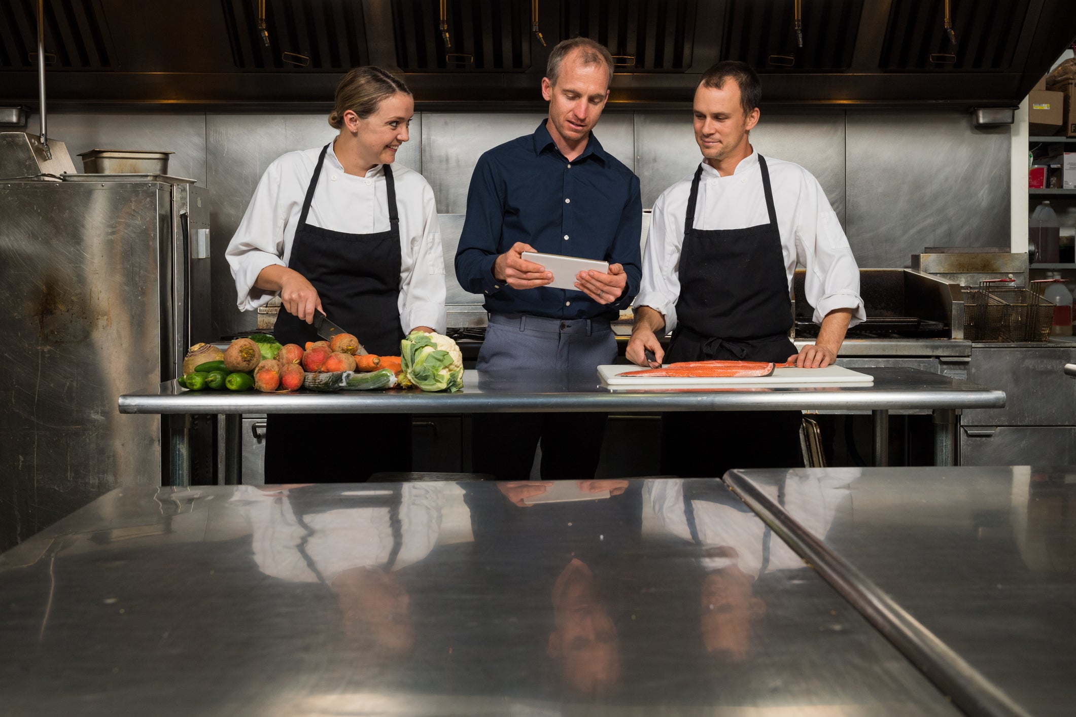 Two men and one woman chef in a professional kitchen