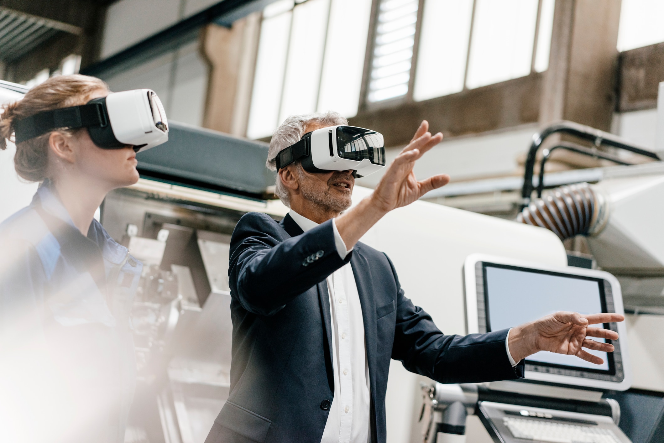Man and a woman in suits, with virtual reality goggles on