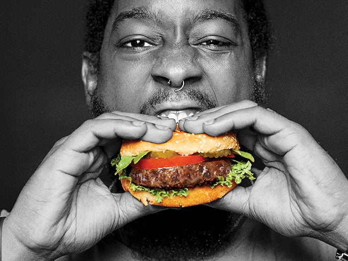 A person is eating a Sweet Earth Plant-Based Awesome Burger