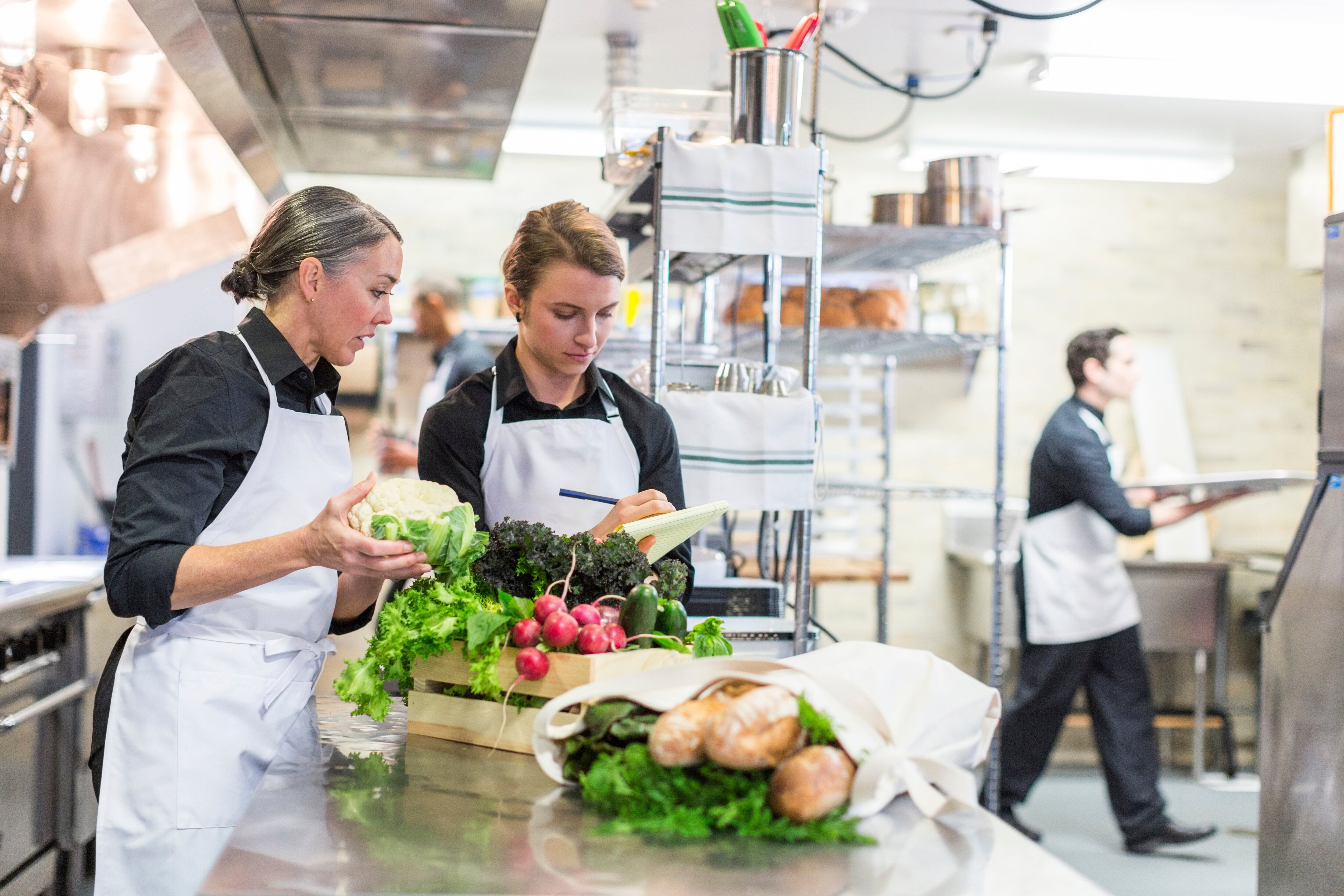 Two female chefs in a professional kitchen with fresh food on the table