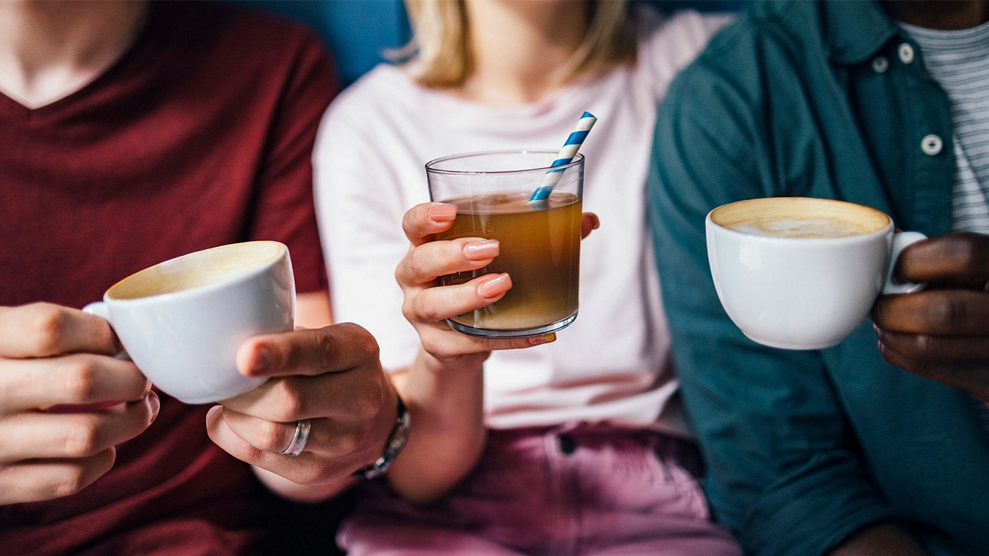 men and a woman holding hot and iced coffee in a cup and mug