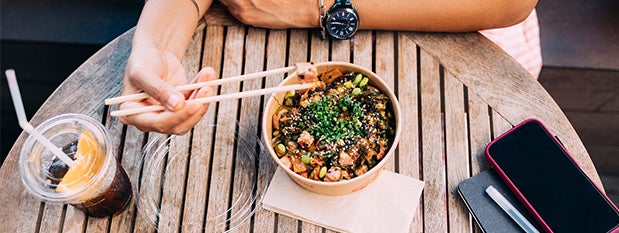 person sitting at a table eating with chopsticks