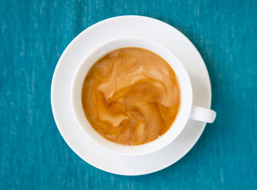 cup of hot coffee with saucer and Coffee mate creamer