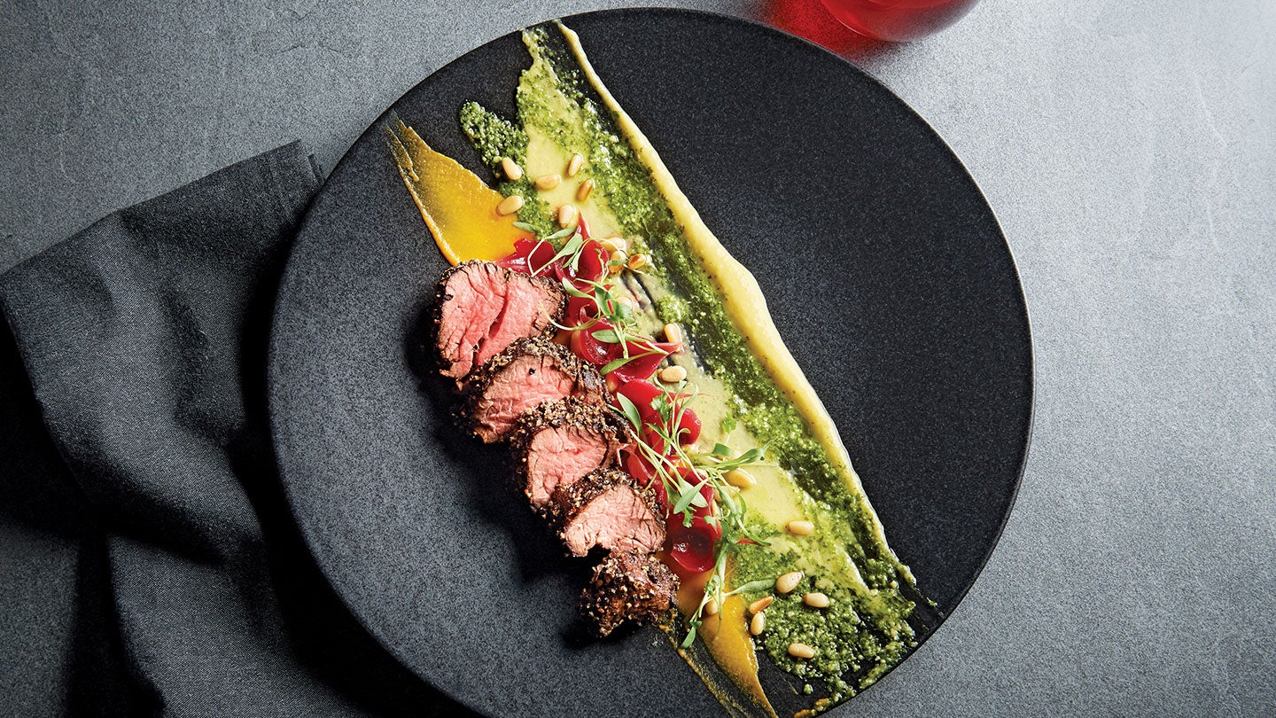 cut up steak with vegetables on black round plate