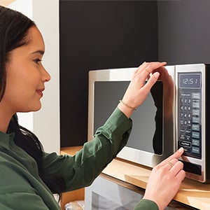 woman pressing buttons on microwave