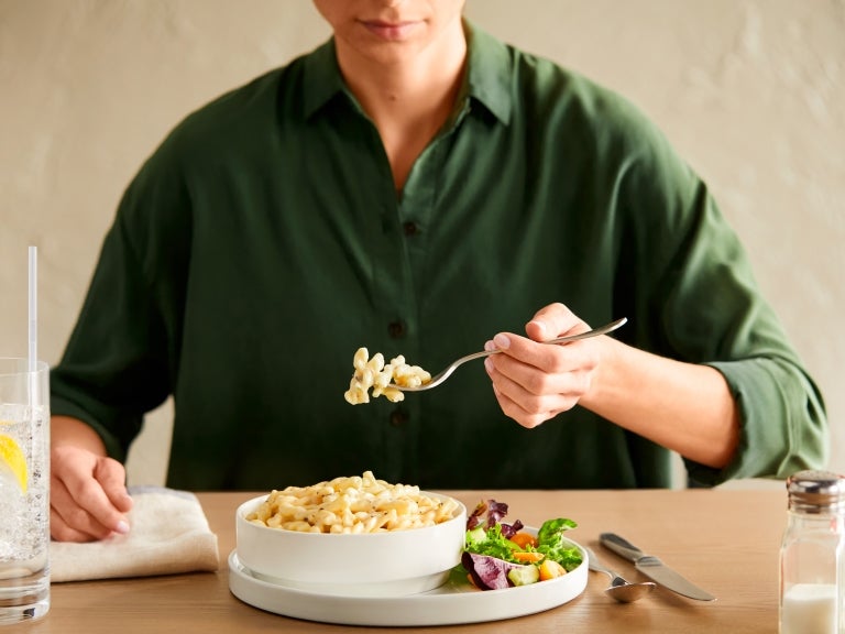 man holding a fork with macaroni and cheese on it