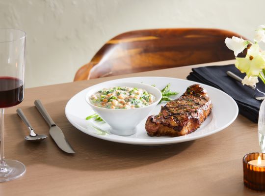 Risotto style farro on white dish with steak