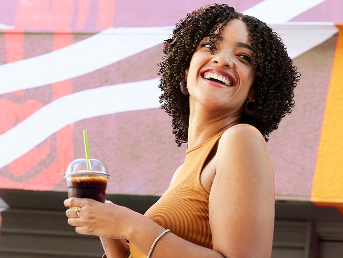 A woman holding a drink and smiling