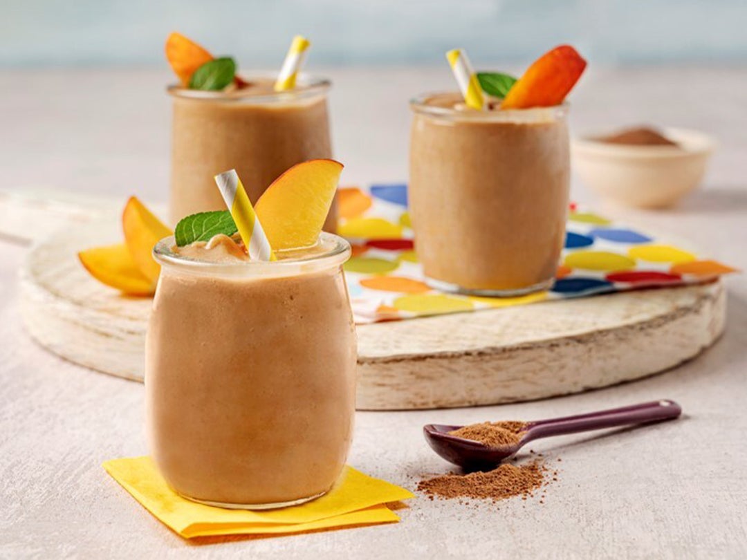 Three frozen hot chocolate beverages, each featuring a peach slice, mint leaf garnish and paper straw