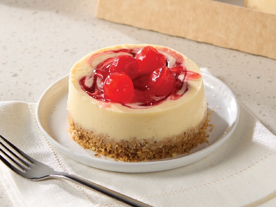 single serve cheesecake on plate with cherries on top and crumble crust