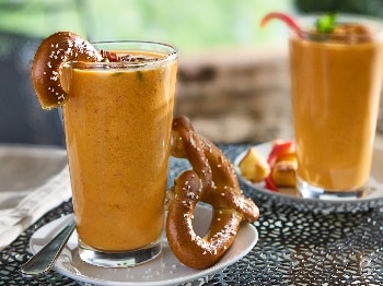 pretzels on side of pumpkin soup in clear glass