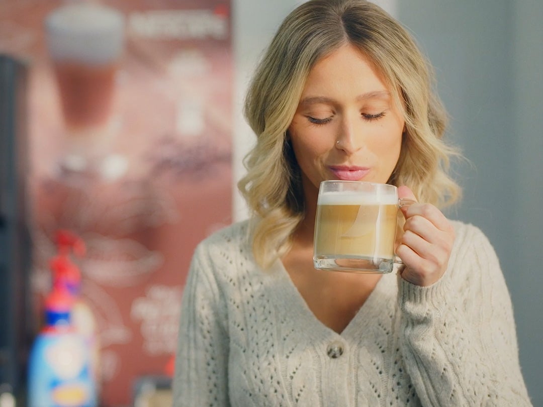 woman holding hot coffee in clear cup about to drink