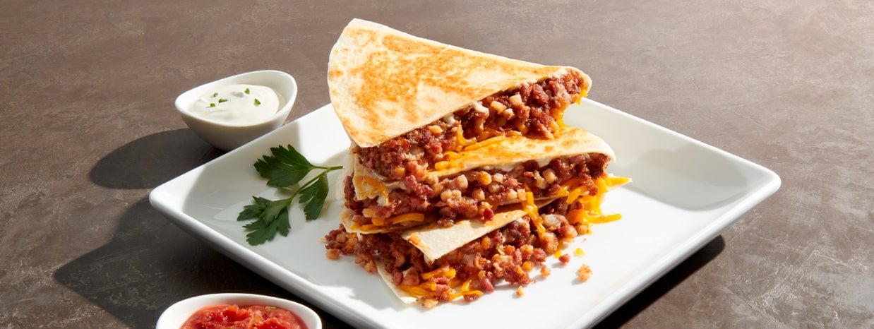 chef-mate stack of three quesadillas on white plate with salsa and sour cream