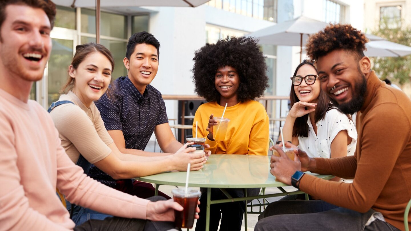 six friends gathered around a table smiling