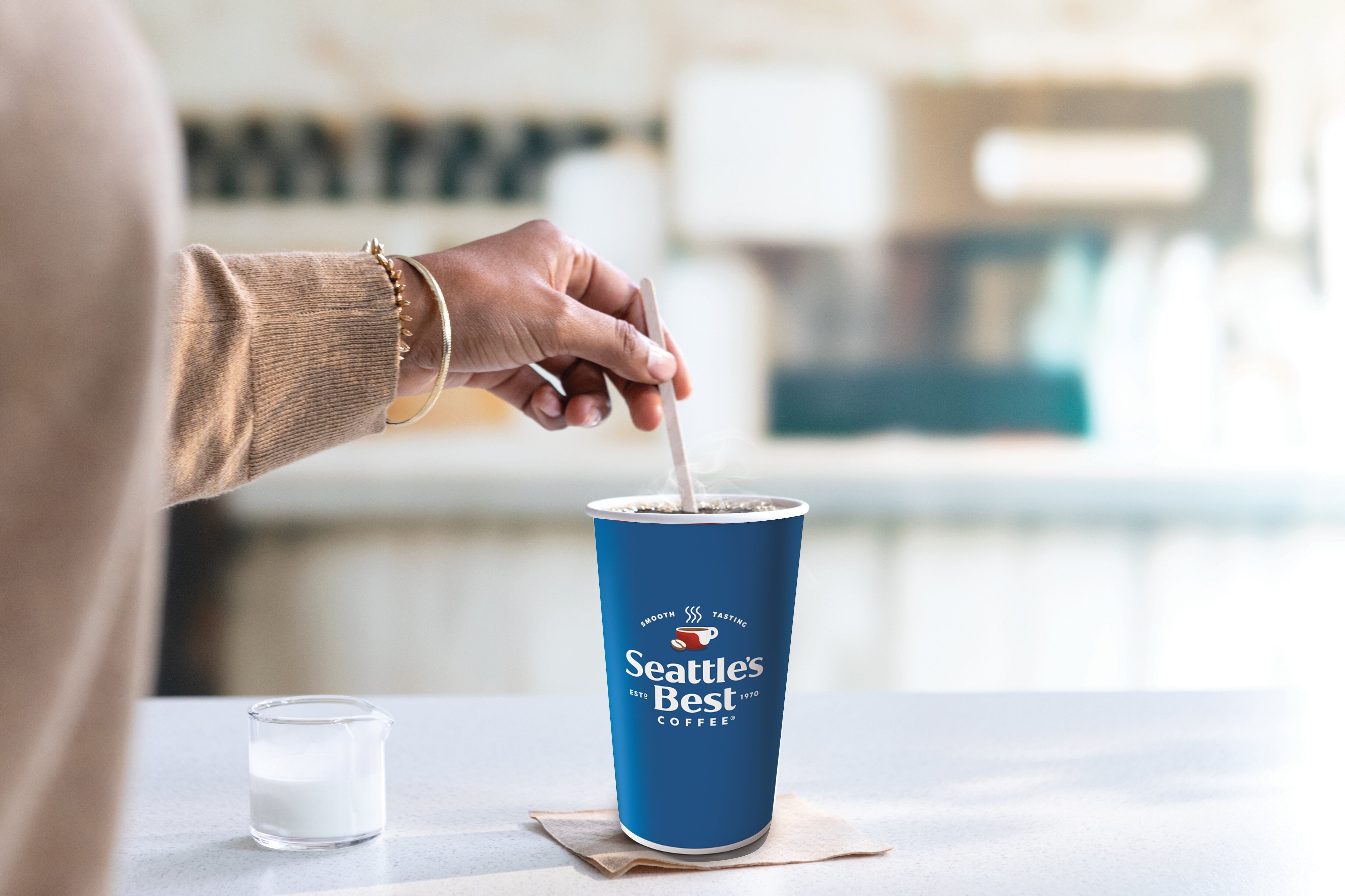 woman stirring creamer in seattle's best cup
