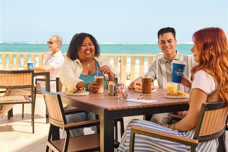 Group of people sitting outside at tables with SBC coffee