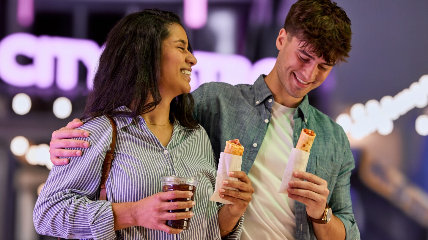 man and woman walking while holding grab and go food