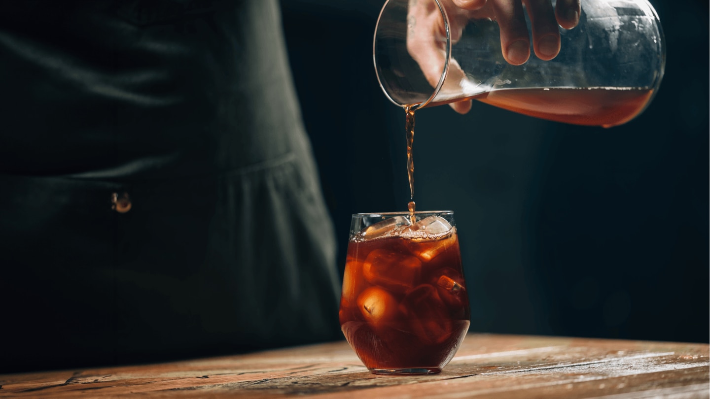 pouring iced coffee into a cup
