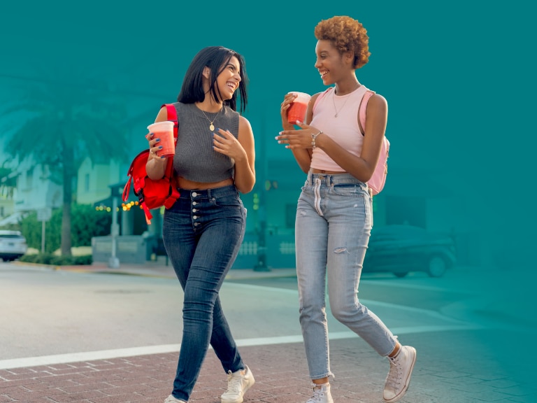 two women walking with drinks in hand