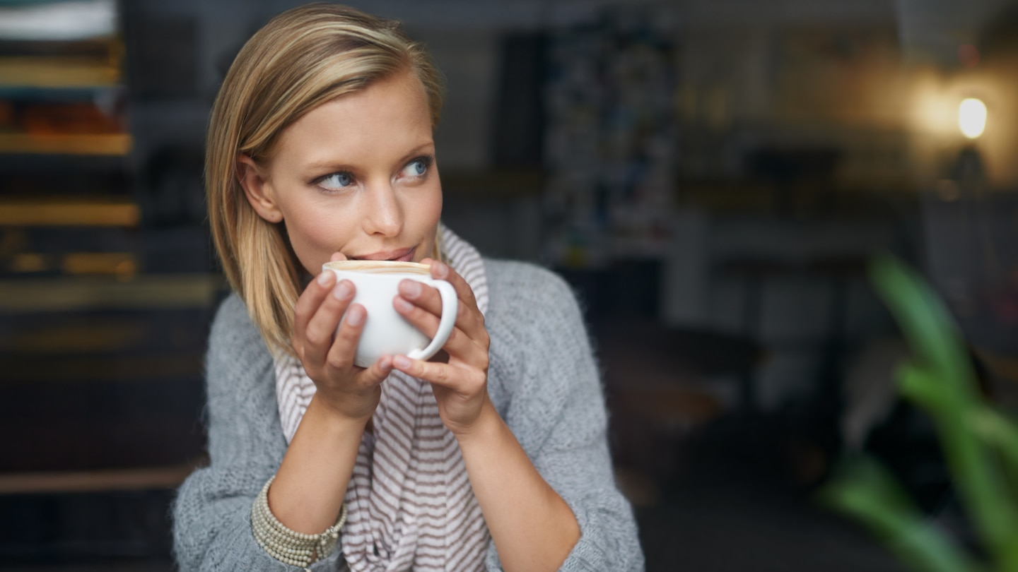 Hotel guest enjoying a warm beverage from a white coffee cup as part of a high-quality hotel beverage program.