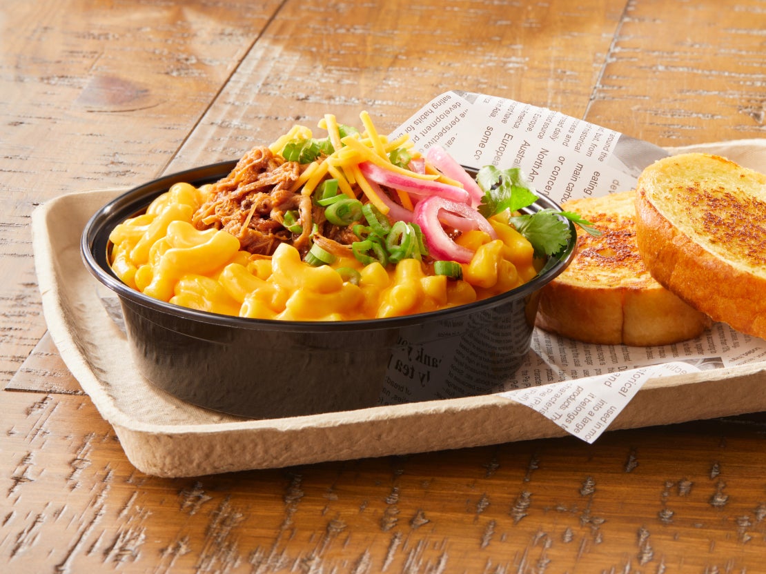 A bowl of creamy mac &amp; cheese topped with pulled pork