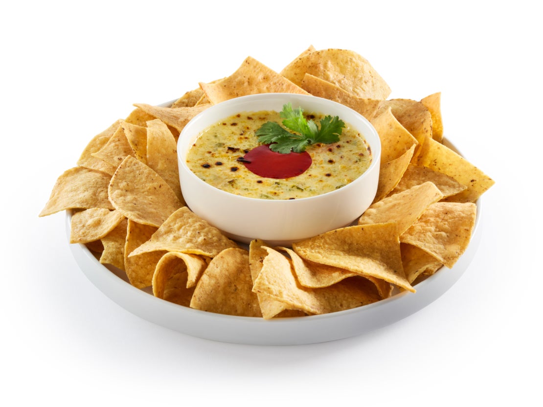 A large plate of chips with a bowl of sauce in the middle