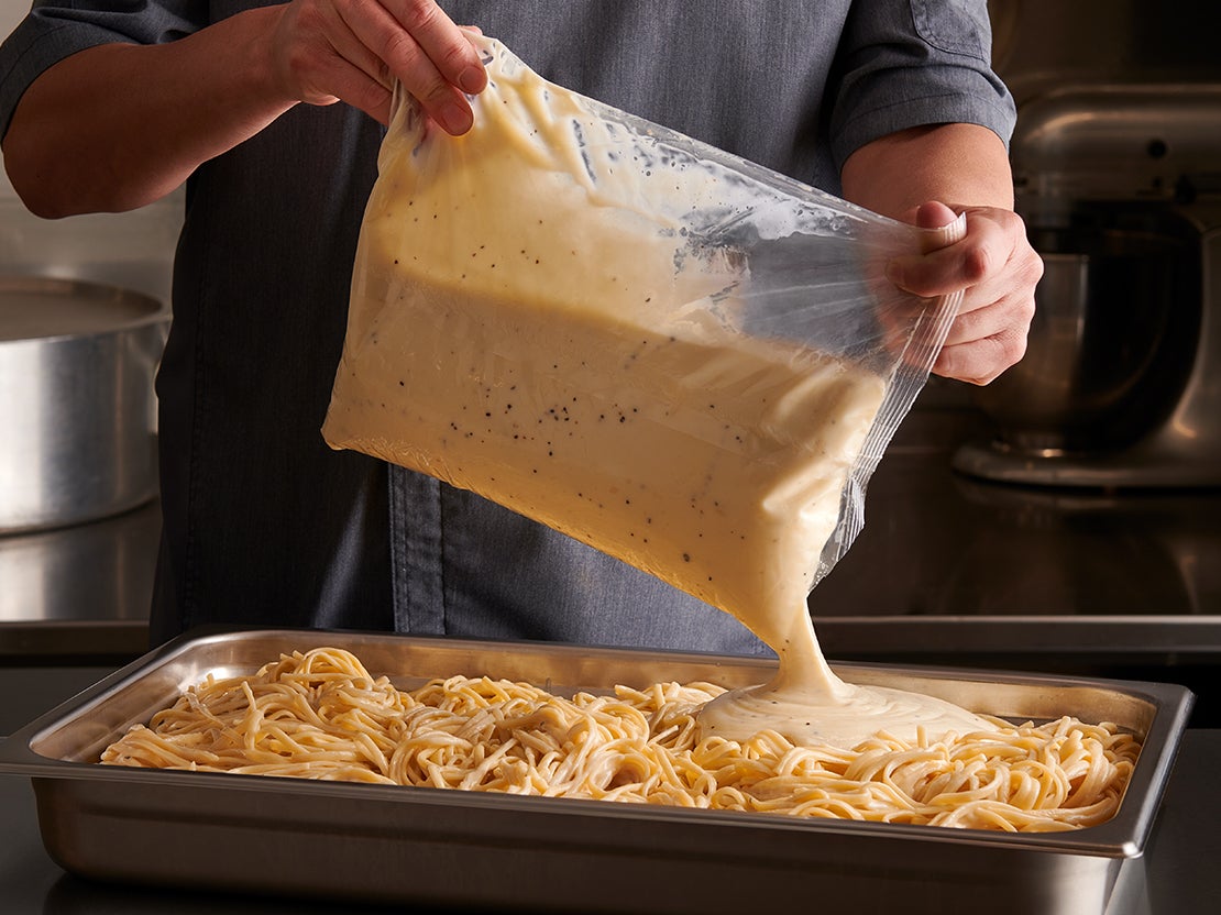 Pouch of sauce being poured on pasta