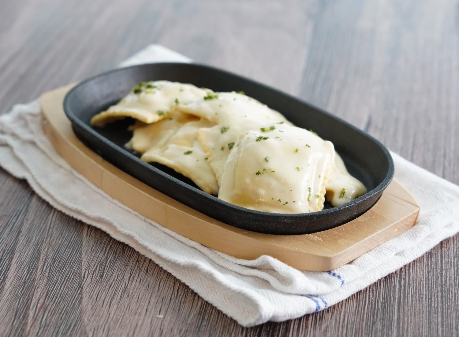 A cast iron dish with ravioli in it.