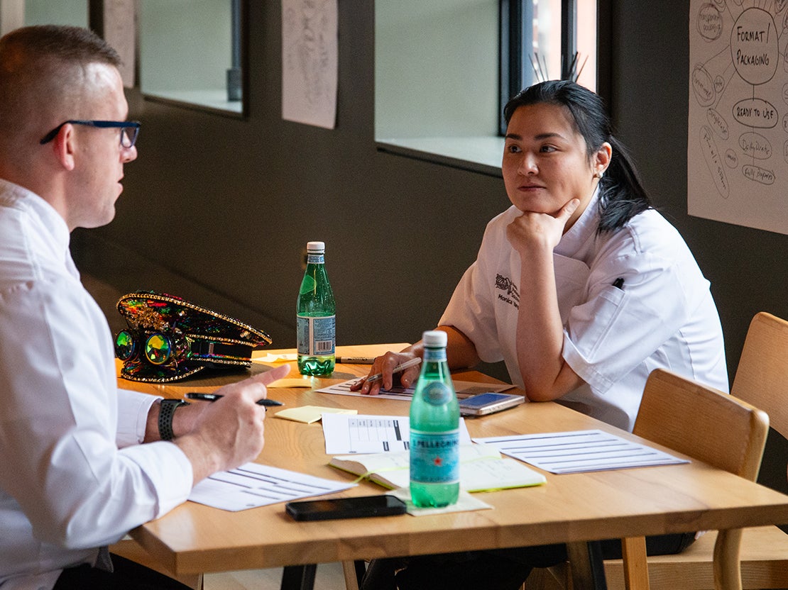 A man and woman sitting at a table with bottles of sparkling water