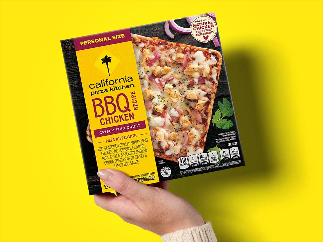 hand holding CPK pizza in packaging