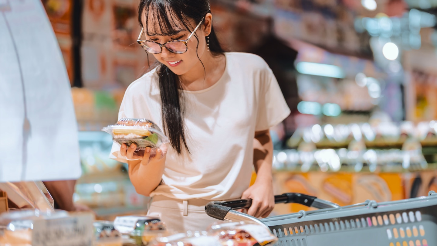 woman with shopping cart holding grab and go food option