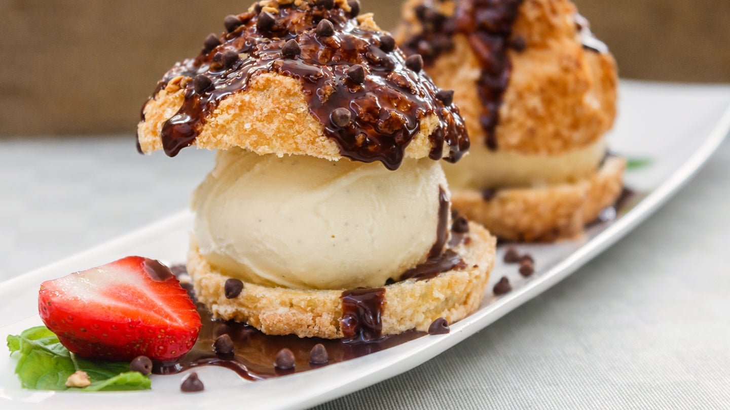 Two shortcake vanilla ice cream sandwiches topped with mini chocolate morsels, nuts and fudge.