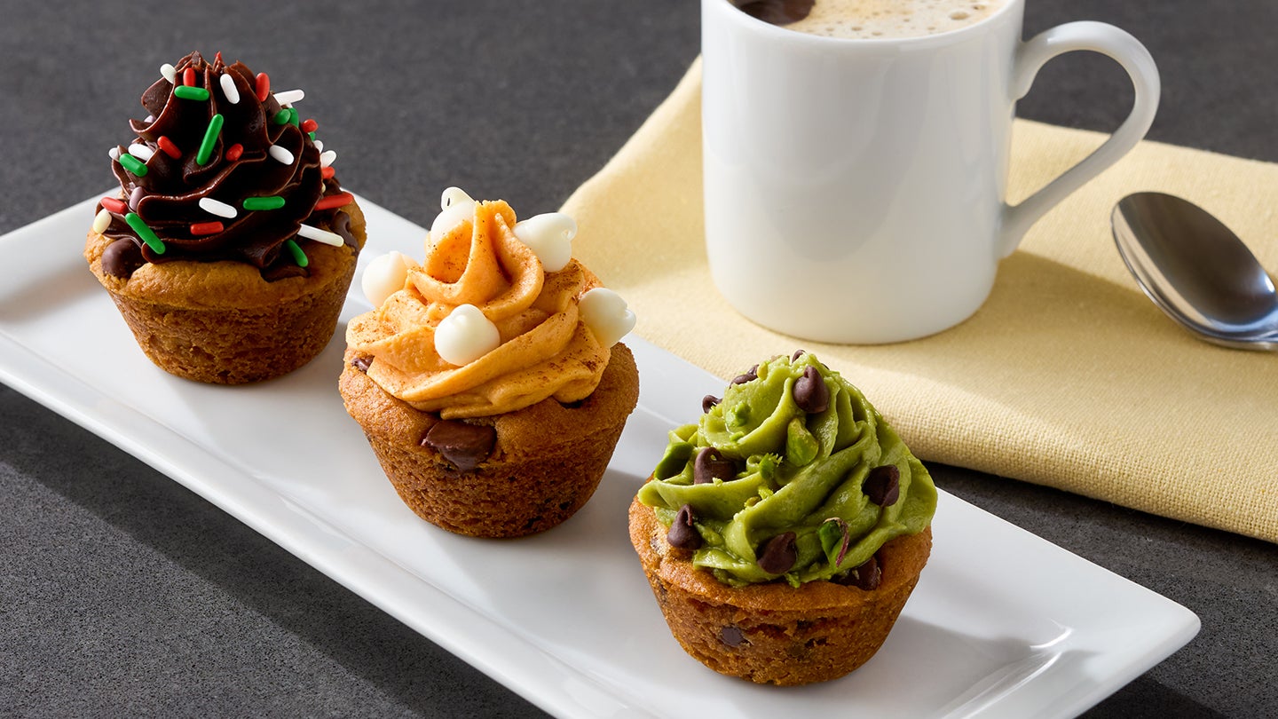 Three mini cookie cups plated next to a cup of coffee.