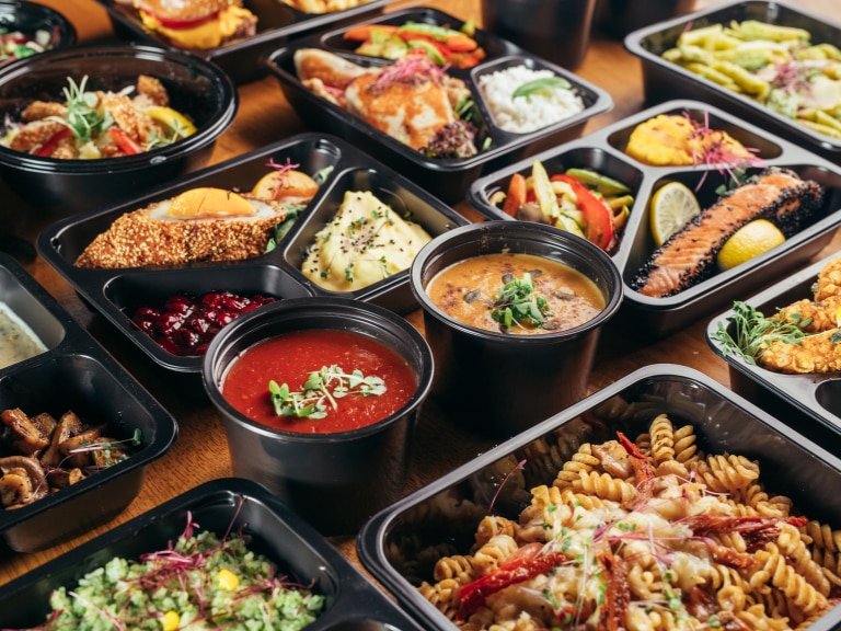 pans of salad pasta and soups on wooden table