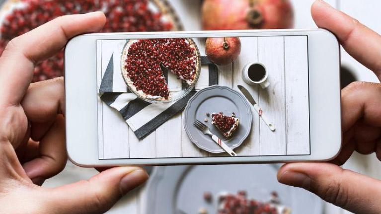 Smart phone capturing plate of dessert with beverage