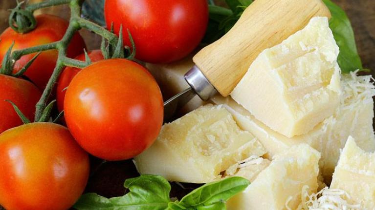 Fresh parmesan cheese with tomatoes and basil on wooden board