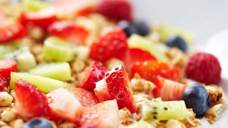 Breakfast plate with fresh fruit on muesli and yogurt